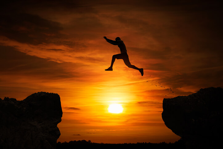 a man jumping between two mountains